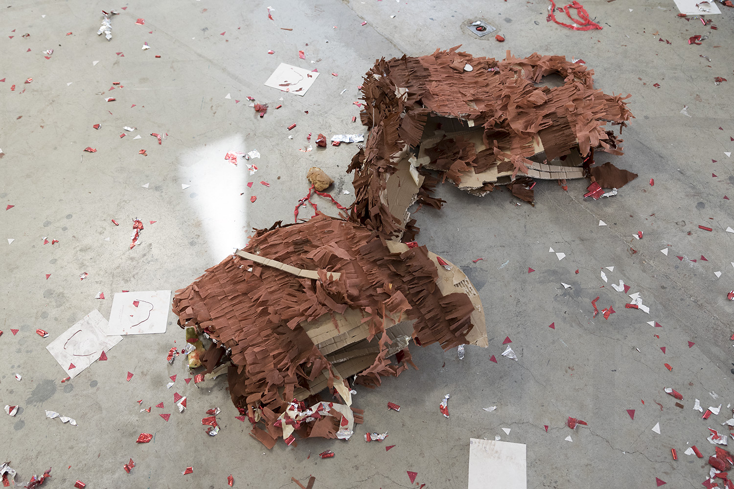 photo du lendemain : la piñata éventré au sol entourée de cotillons et de feuilles de dessins de mammouth.